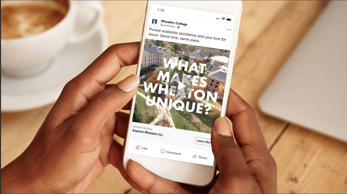 A smartphone displaying a play video button over text that reads, "What Makes Wheaton Unique"